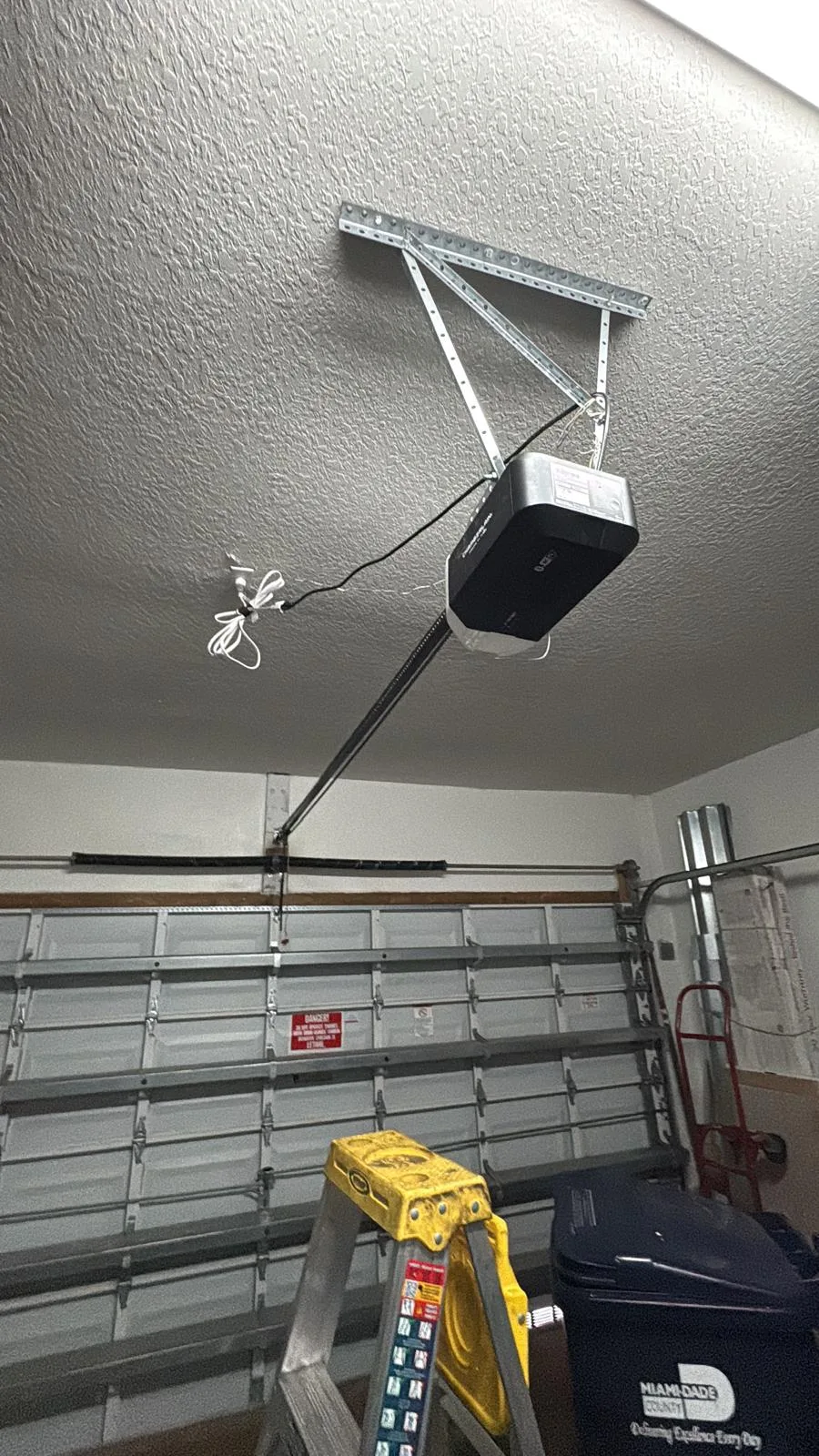 Ceiling-mounted garage door opener and rail above a closed sectional door