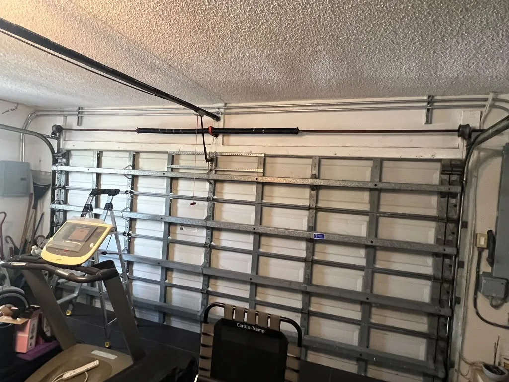 Torsion spring assembly above the inside of a sectional garage door