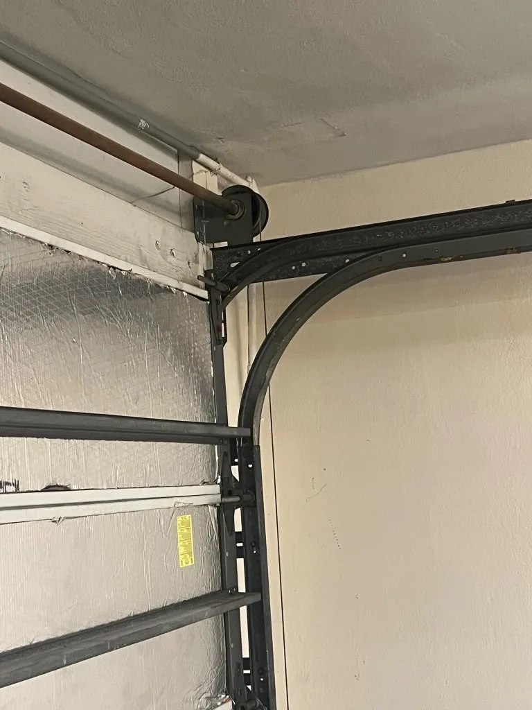 Curved garage door track with rollers and torsion shaft visible